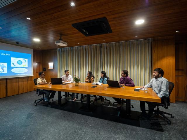 Business discussion in the boardroom of Nine o Six Advisory featuring a sleek wooden interior.