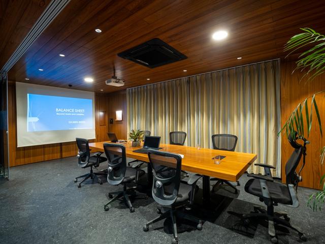 Nine o Six Advisory professional conference room with a projector screen, wooden interiors, and modern office chairs.